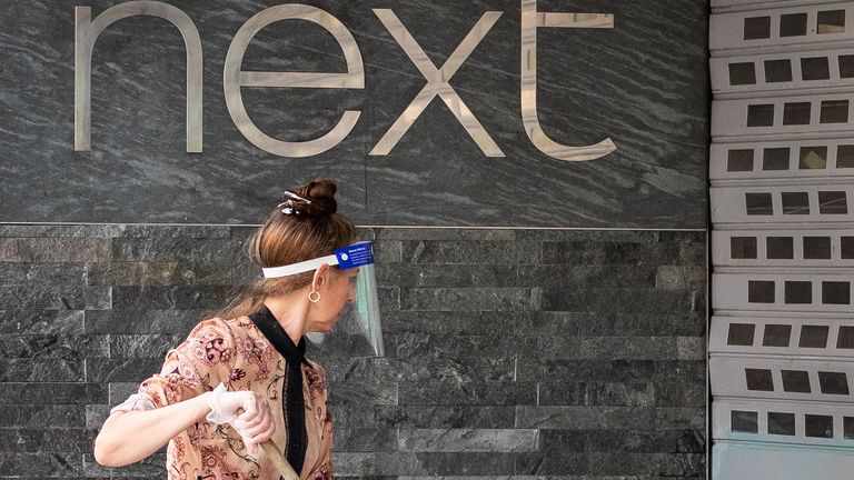 A shop worker cleans the exterior of a Next retail shop on Oxford Street following the introduction of measures to bring England out of lockdown. 11/6/2020