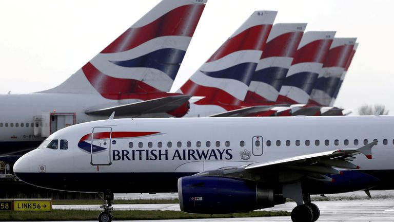 FILE PHOTO: A British Airways plane taxis past tail fins of parked aircraft near Terminal 5 at Heathrow Airport in London, Britain, March 14, 2020