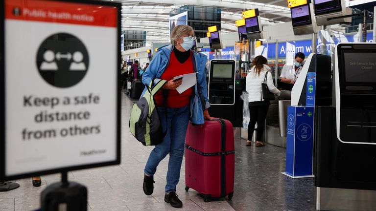 A passenger walks with her luggage at the Terminal 5 departures area at Heathrow Airport in London