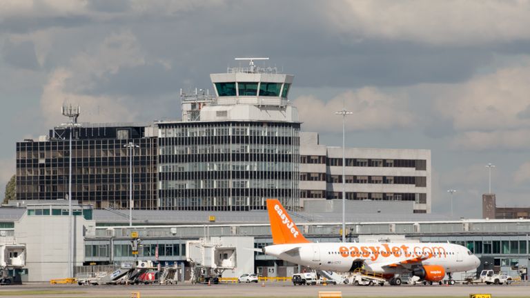 Manchester, United Kingdom - August 27, 2015: Manchester Airport Terminal and easyJet Airbus A319 passenger plane parked. Air control tower on the background.