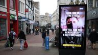 People make their way past a government coronavirus sign on Old Christchurch road in Bournemouth, Dorset, during England's third national lockdown to curb the spread of coronavirus. Picture date: Tuesday February 16, 2021.