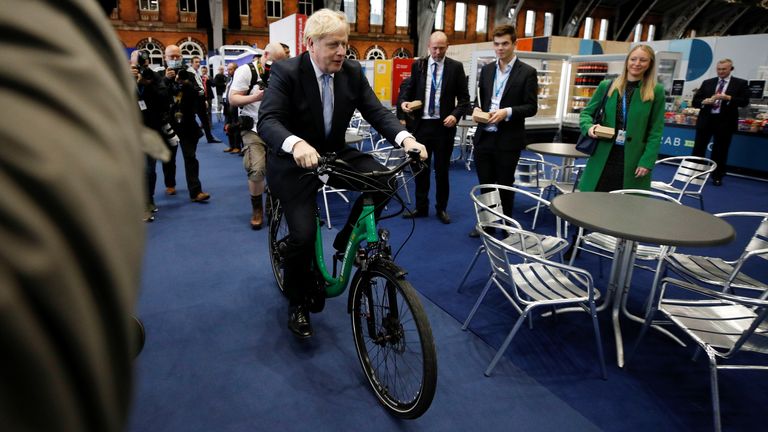 Britain's Prime Minister Boris Johnson sits on a bike as he visits a trade stall inside the conference venue at the annual Conservative Party conference, in Manchester, Britain, October 5, 2021. REUTERS/Phil Noble
