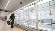 A shopper looks at produce and empty shelves of the meat aisle in Co-Op supermarket, Harpenden