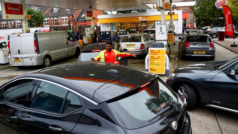 A worker guides cars into the forecourt as vehicles queue to refill at a fuel station in London, Britain, September 30, 2021. REUTERS/Hannah McKay
