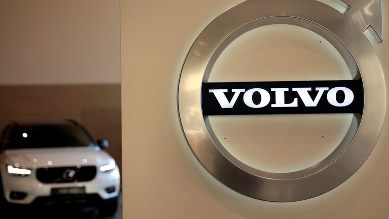 In this Feb. 6, 2020 file photo a Volvo car is parked behind the Volvo logo in the lobby of the company's corporate headquarters, in Brussels