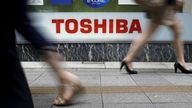 FILE PHOTO: Pedestrians walk past a logo of Toshiba Corp outside an electronics retailer in Tokyo September 14, 2015.