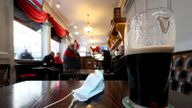 A close up of a pint of Guinness and a face mask on a table in the Richmond pub in Liverpool watch a statement by the Prime Minister Boris Johnson, as parts of the North of England are bracing themselves for the most stringent Tier 3 controls, with Merseyside expected to have its pubs, gyms and casinos closed in a bid to suppress its infection rate.