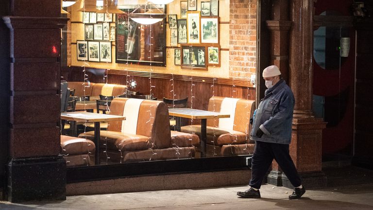 A man walks past a largely empty restaurant in central London on 21 December