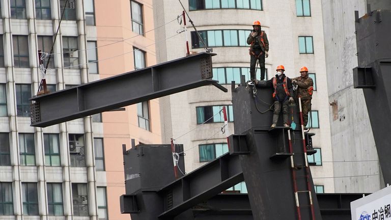 Workers watch as a crane lifts a structure at a construction site in Shanghai, China January 14, 2022