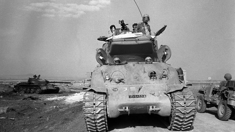 A Israeli tank passes the remains of a Syrian tank in the Golan Heights in Israel during the Yom Kippur War on Oct. 9, 1973. (AP Photo/Spartaco Bodini)