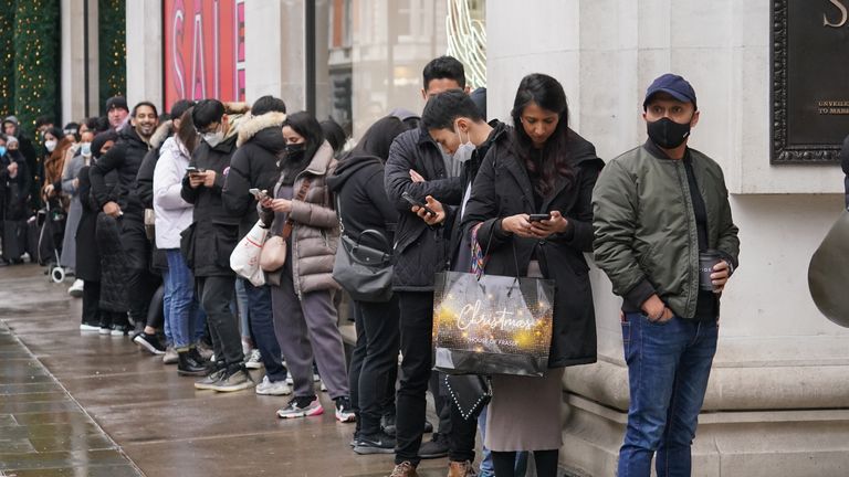 Shoppers stand in line for the doors to open for the start of the Boxing Day sales at Selfridges department store on Oxford Street in London. Consumers are set to shop from home but spend more in the post-Christmas sales than in previous years in a reassuring sign for online retailers, a survey suggests. Picture date: Sunday December 26, 2021.