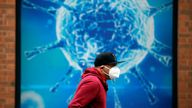 A man wearing a protective face mask walks past an illustration of a virus outside a regional science centre, as the city and surrounding areas face local restrictions in an effort to avoid a local lockdown being forced upon the region, amid the coronavirus disease (COVID-19) outbreak, in Oldham, Britain August 3, 2020