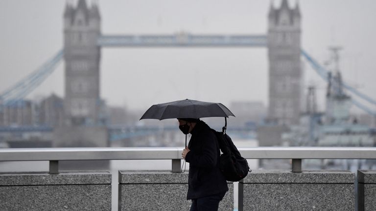 A worker wears a protective face mask as he crosses London Bridge, with Tower Bridge seen behind, during the morning rush-hour, as coronavirus disease (COVID-19) lockdown guidelines imposed by British government encourage working from home, in the City of London financial district, Britain, January 4, 2022. REUTERS/Toby Melville
