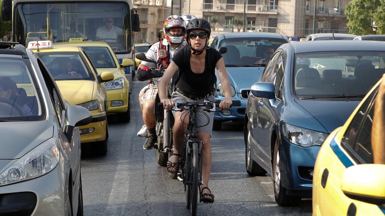 Music saleswoman Elena Koniaraki, 39, rides her bicycle between cars at a central street in Athens July 11, 2012.