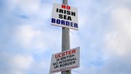 FILE PHOTO: Signs reading 'No Irish Sea border' and 'Ulster is British, no internal UK Border' are seen affixed to a lamp post at the Port of Larne, Northern Ireland, March 6, 2021. REUTERS/Clodagh Kilcoyne/File Photo