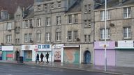 People walk past shuttered shops