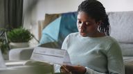 Portrait of a young African American businesswoman reading a utility bill while working remotely from home.