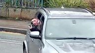 Cowie is seen pointing a gun out of the back window of the car