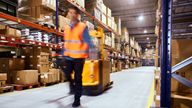 Warehouse, worker with a forklift in motion blur.