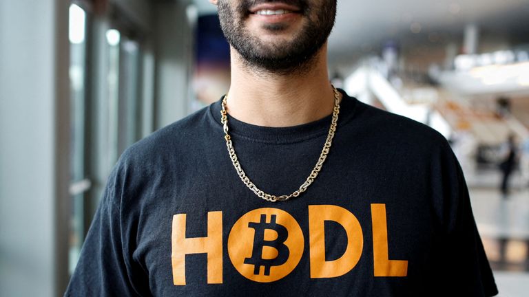 A Bitcoiner wears a T-shirt that says 'HODL' - encouraging people to hold on to their crypto. The slogan's inspired by a typo made on a Bitcoin forum years ago