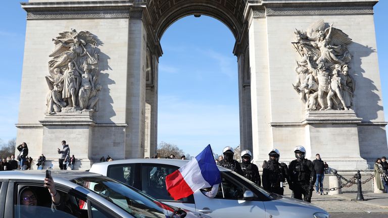 Protesters part of a convoy drives past the Arc de Triomphe on the Champs-Elysees avenue, Saturday, Feb.12, 2022 in Paris. Paris police intercepted at least 500 vehicles attempting to enter the French capital in defiance of a police order to take part in protests against virus restrictions inspired by the Canada's horn-honking 