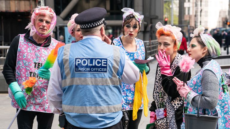 Activists from Extinction Rebellion dressed as cleaners speak to a police liaison officer outside Lloyds of London, in the City of London, as they call for Lloyds to stop insuring fossil fuel projects worldwide. Picture date: Tuesday April 12, 2022.