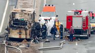 Firefighters and forensic workers inspect the scene of a bus crash on a highway near the village of Bosnek, western Bulgaria, Tuesday, Nov. 23, 2021. A bus carrying tourists back to North Macedonia crashed and caught fire in western Bulgaria early Tuesday, killing at least 45 people, including a dozen children, authorities said. (Minko Chernev/BTA Agency Bulgaria via AP)