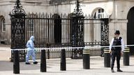 A police forensic official walks outside the Horse Guards building as a police officer stands guard at the cordoned-off area on Whitehall in Westminster after the road was closed by police following an incident involving the arrest of a man near Downing Street, in London, Britain, April 18, 2022. REUTERS/Henry Nicholls
