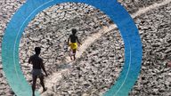 A man and a boy walk across an almost dried up bed of river Yamuna following hot weather in New Delhi, India, Monday, May 2, 2022. An unusually early and brutal heat wave is scorching parts of India, where acute power shortages are affecting millions as demand for electricity surges to record levels. (AP Photo/Manish Swarup)


