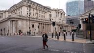 A person wears a face mask while walking crossing a road outside the Bank of England,  
Pic:AP