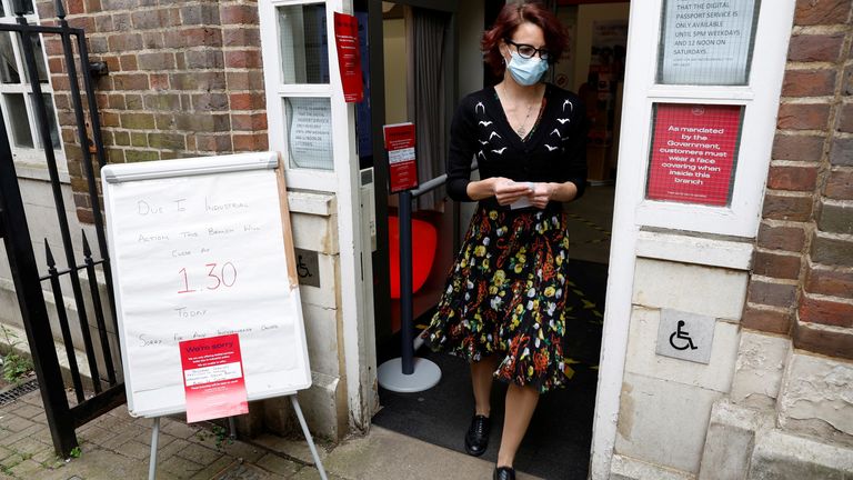 A woman walks past a sign informing customers of a Post Office branch closure due to industrial action, in St Albans, Britain, May 3, 2022. REUTERS/Peter Cziborra
