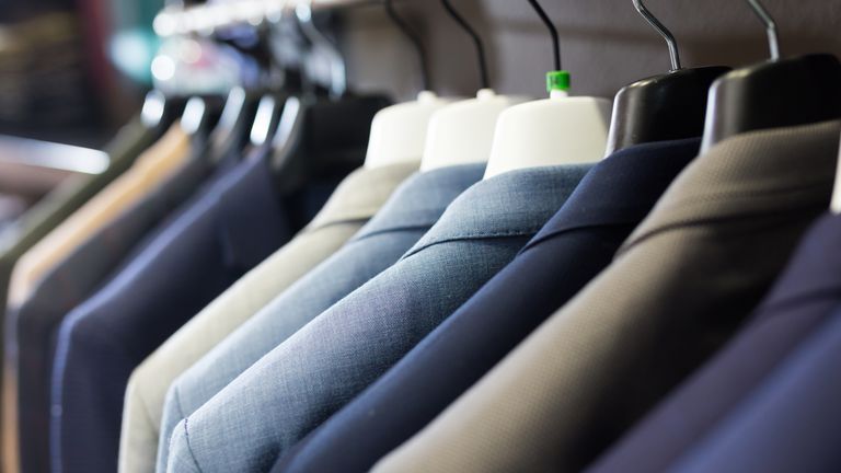 Assortment of suit jackets on hanger racks in menswear clothing store for selling