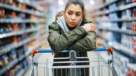 Young woman buying in supermarket and feeling worried about increase in food prices. 