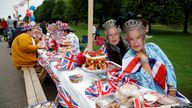 People dressed in outfits with a Union Jack theme and masks depicting Britain's Queen Elizabeth gather around a picnic table as they take part in the Big Jubilee Lunch on The Long Walk as part of celebrations marking the Platinum Jubilee of Britain's Queen Elizabeth, in Windsor, Britain, June 5, 2022. REUTERS/Peter Nicholls
