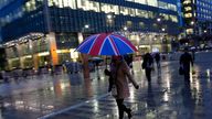 Workers walk in the rain at the Canary Wharf business district in London November 11, 2013.