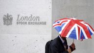 A worker shelters from the rain under a Union Flag umbrella as he passes the London Stock Exchange in London, Britain, October 1, 2008. REUTERS/Toby Melville/File Photo