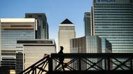 An early morning walker on a bridge in front of the Canary Wharf skyline, in East London.