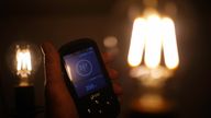 A handheld SSE smart meter for household energy usage is held next to an energy-efficient LED light bulb. Families across Great Britain will find out on Friday how tough energy bills will be this winter but they may have to wait to discover what the Government will do to help Picture date: Thursday August 25, 2022.

