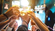 Group of happy friends drinking and toasting beer at brewery bar restaurant - Friendship concept with young people having fun together at cool vintage pub - Focus on middle pint glass - High iso image