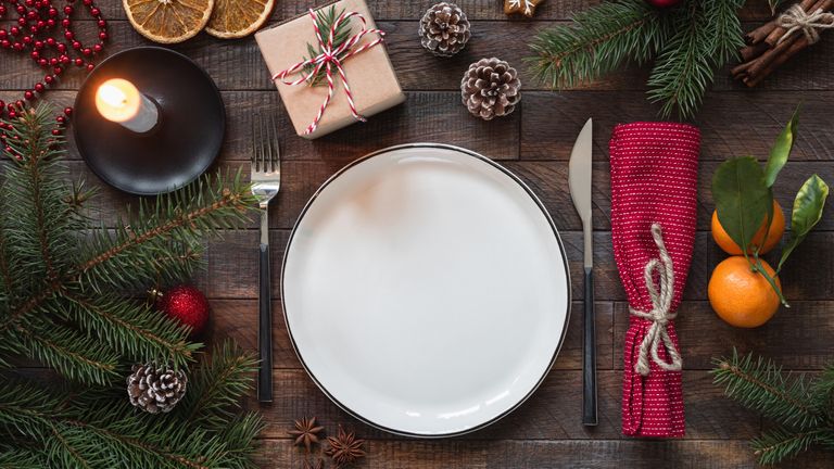 Authentic Christmas Table Setting. Empty Plate, Candles, Silverware, Fir tree, Gift boxes. Top view with copy space for text