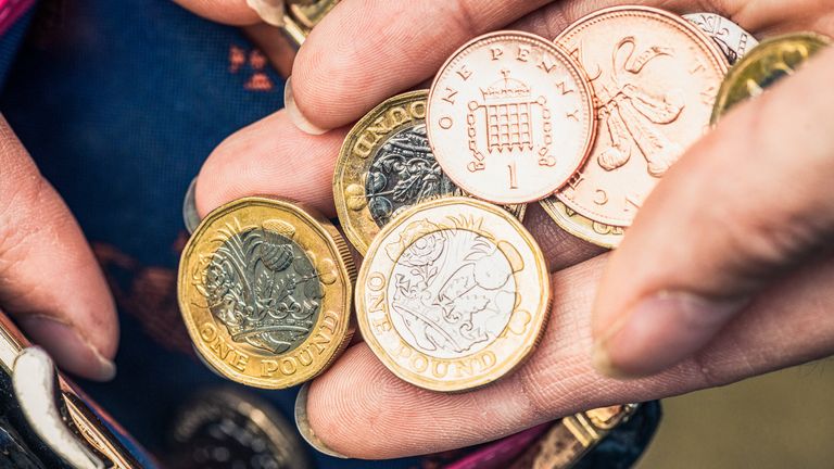 Close-up of a woman's hand holding one pound coins and other change from her purse.