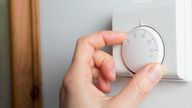 Close Up Of Female Hand On Central Heating Thermostat