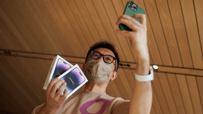 A man takes a selfie with two iPhone 14 as Apple Inc's new models go on sale at an Apple store in Beijing, China, September 16, 2022. REUTERS/Thomas Peter