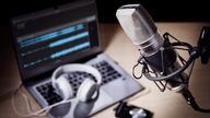 Podcast microphone, laptop computer camera and headphones on desk in recording studio