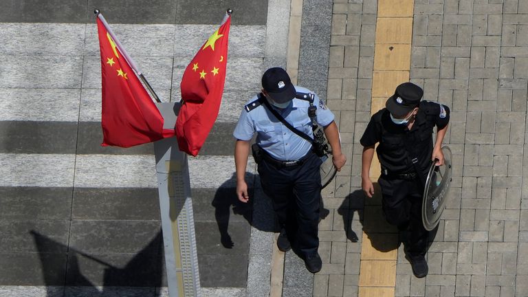 A police man and security guard walks past Chinese flags outside the Evergrande headquarters in Shenzhen, China 
pIC:AP