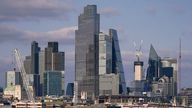 Commuters walk along Waterloo Bridge, against the backdrop of the skyline of the financial district of the City of London, Monday, June 5, 2023. (AP Photo/Alberto Pezzali)