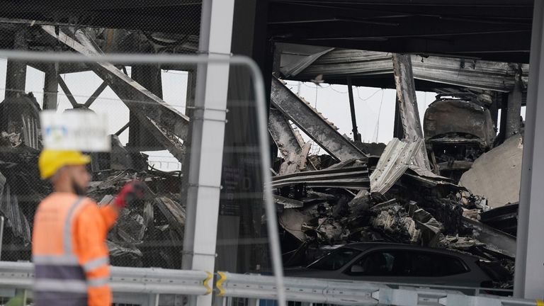 The burnt out shells of cars, buried amongst debris of a multi-storey car park at Luton Airport 