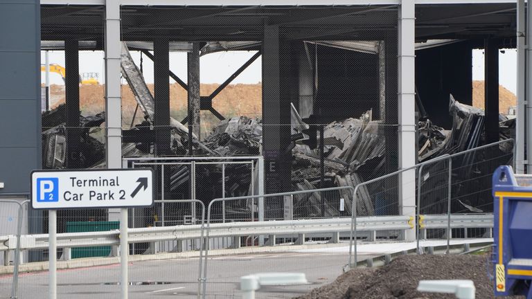 The burnt out shells of cars, buried amongst debris of a multi-storey car park at Luton Airport 