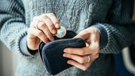 Hands holding british pound coin and small money pouch