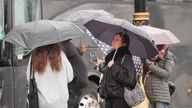 People shelter from the rain on the Embankment in London.